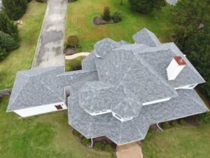 Aerial view of a very large home with a gray shingle roof by roof installers near me.