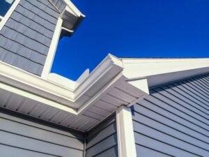 Low angle view of new soffit gutters on a blue siding house by gutter installers near me.