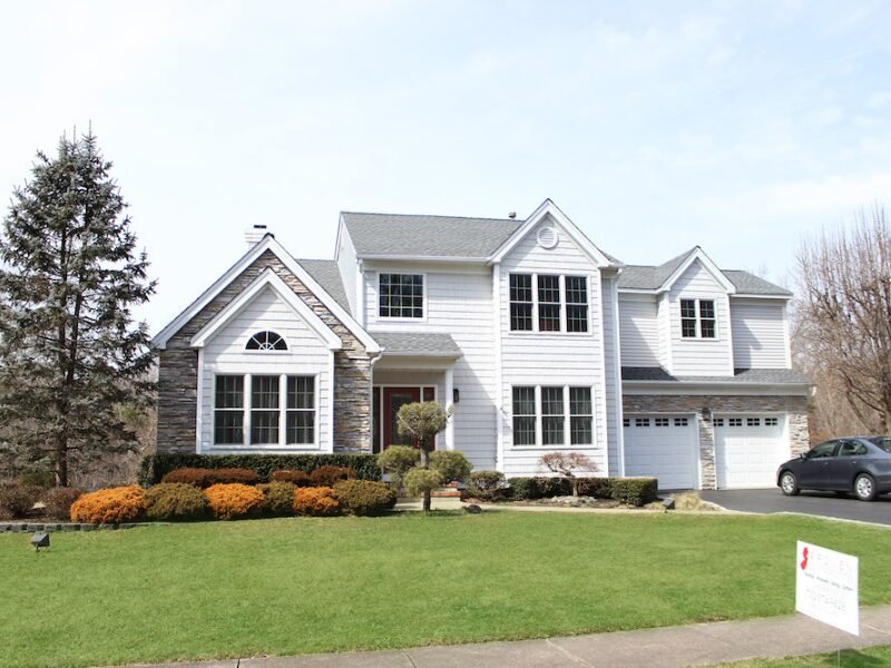 Street view of a large white siding home with a new roof by residential roofing companies near me.